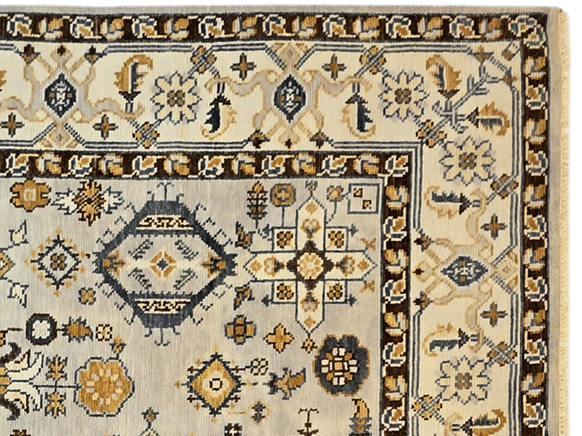 Close-up of Oushak rug detailing: beige field with navy outlines and gold starburst ornaments.