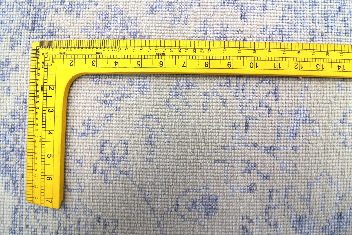 Ice blue rug with distressed pattern, measured with yellow tape along the surface