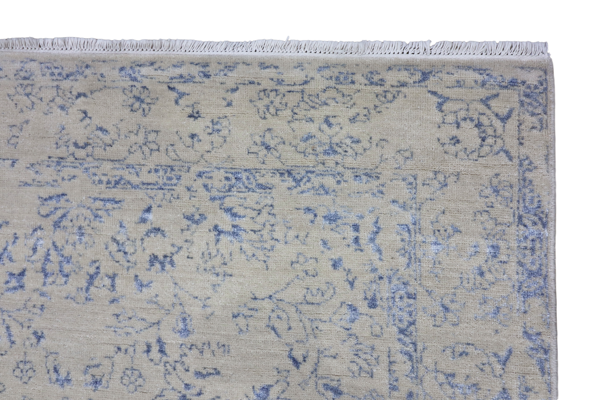 Ice blue rug close-up with distressed floral motif and light textured pile