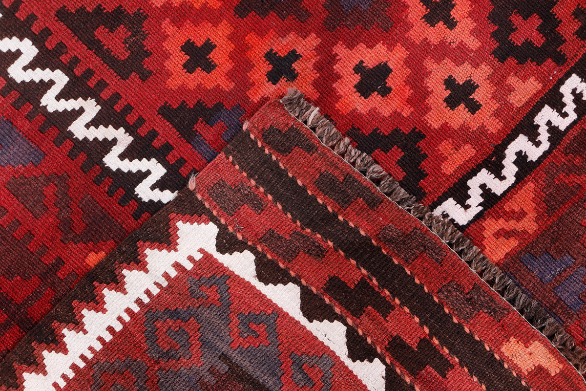 Red kilim rug corner detail with striped weave texture and short fringe edging