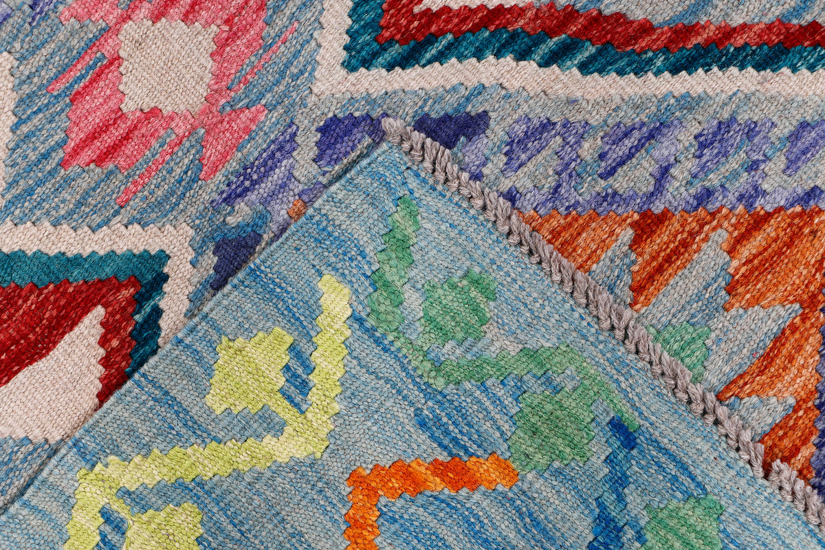 Kilim rug corner with geometric pattern in blue, purple, orange, and red; woven pile