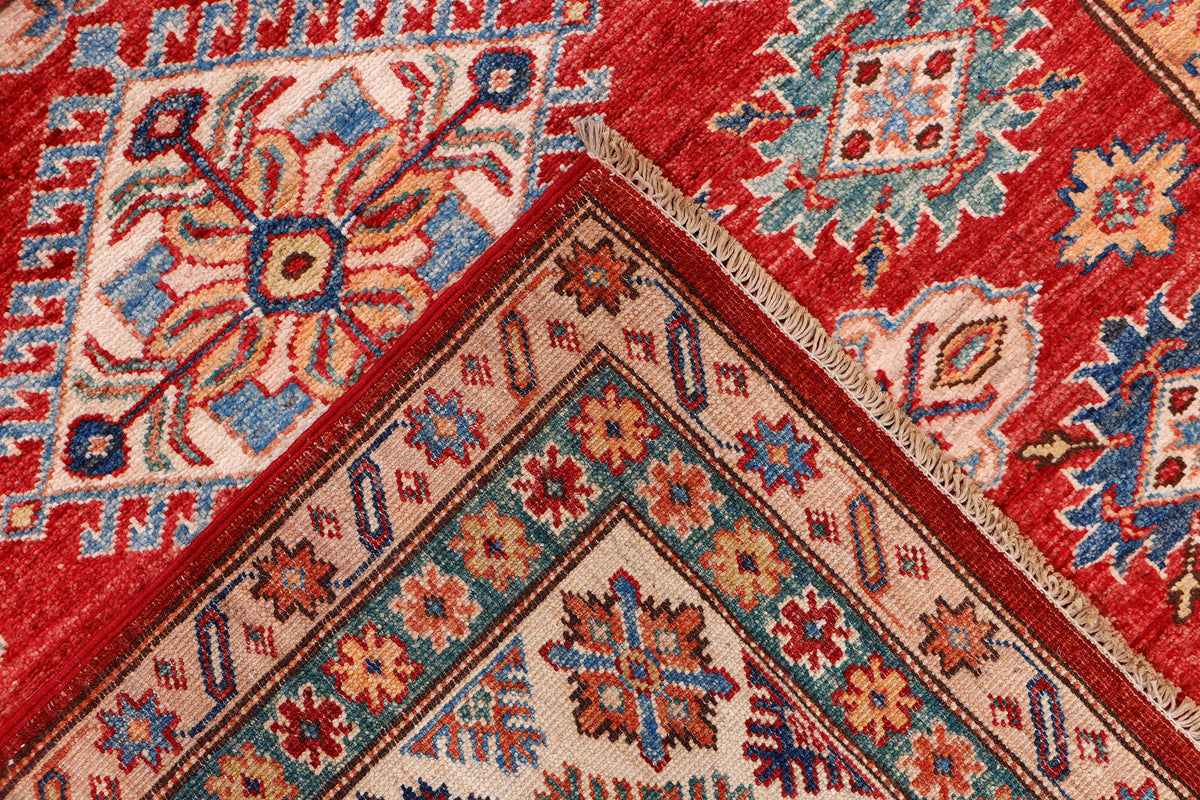Red Kazak rug corner view with geometric stars and multicolor border, 198x155 cm