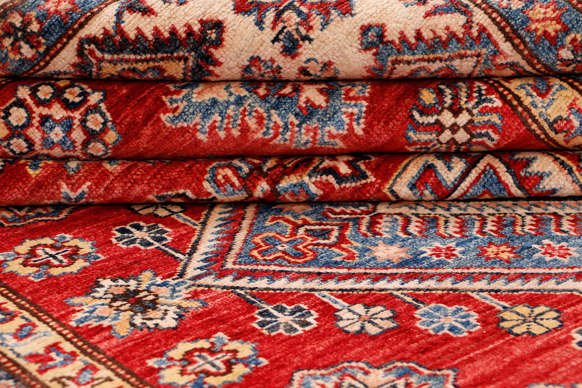 Folded Kazak rug detail with red field and blue-and-ivory geometric motifs