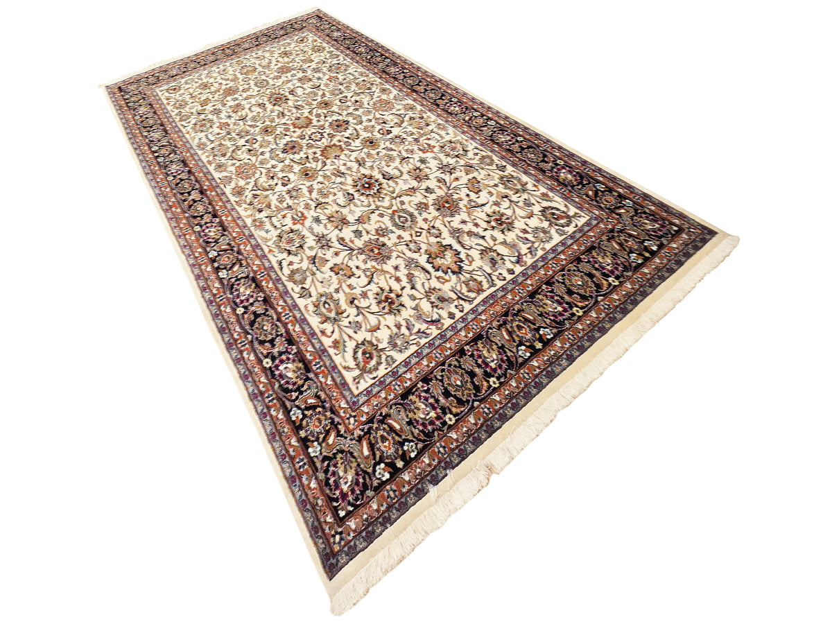 Diamond-tilted cream and floral rug with dark navy decorative border, fringes