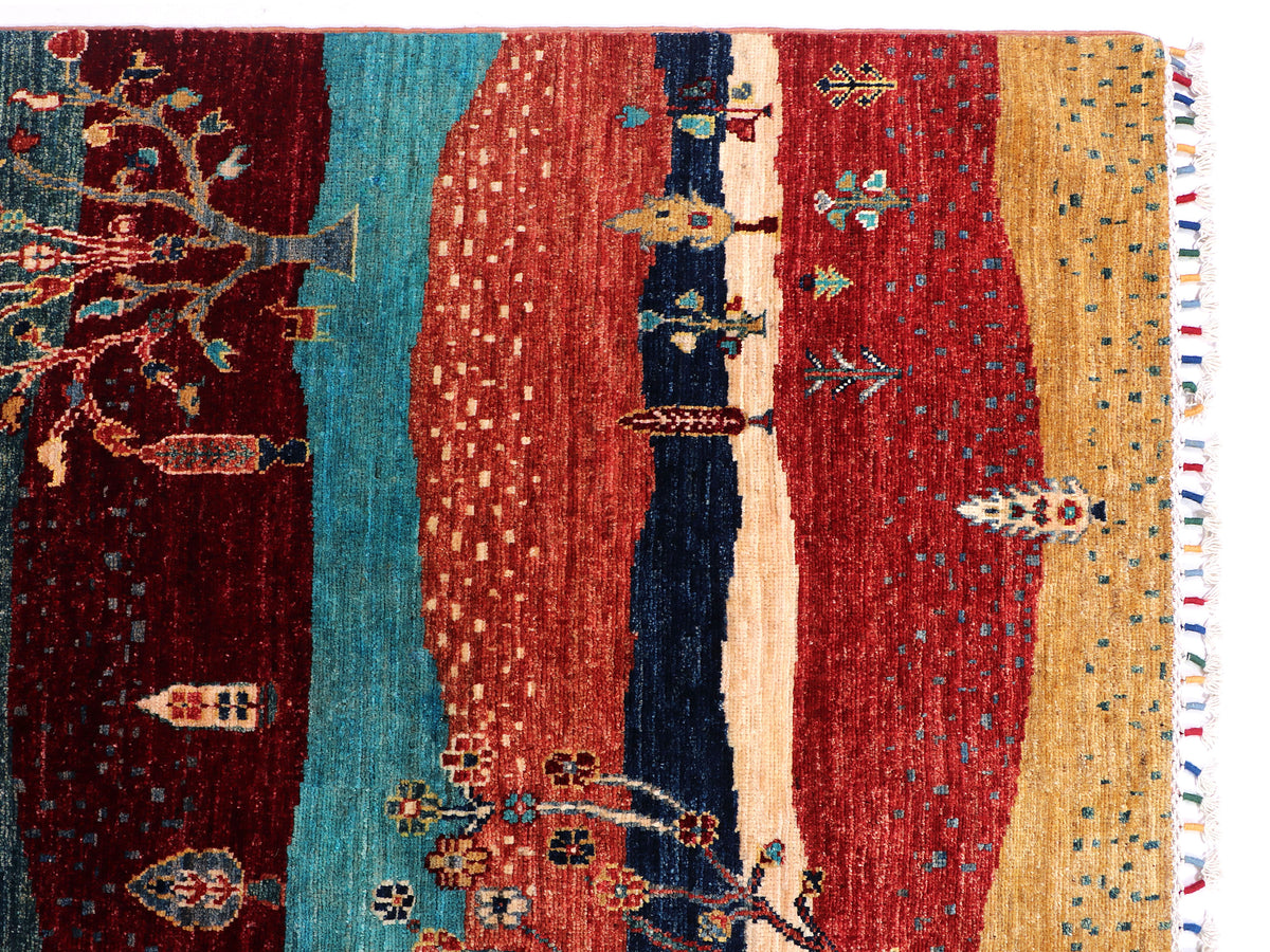 Ariana Gabbeh rug fabric close-up with deep red, teal, and cream pattern details.