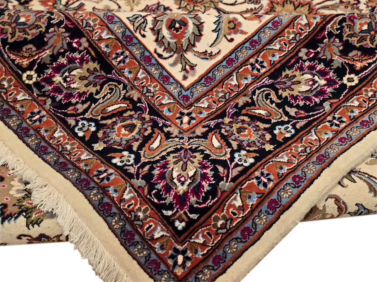 Close-up corner of dark navy floral rug with rust and magenta accents