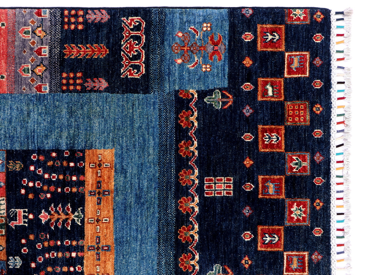 Gabbeh Afghan rug detail view with navy blue blocks, medallion shapes, and fringe