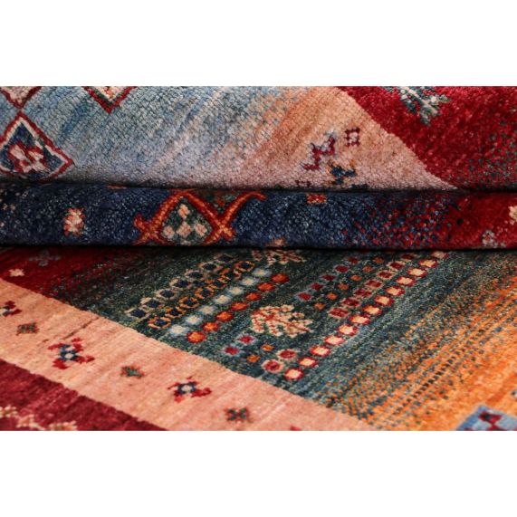 Rug close-up showing red, teal, and beige patchwork bands with woven details