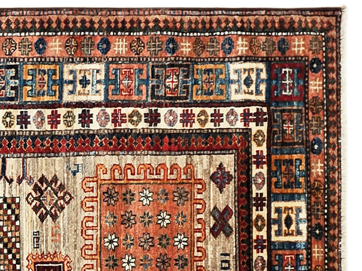Kazak-style rug border close-up with repeating geometric motifs in blue, red, and cream