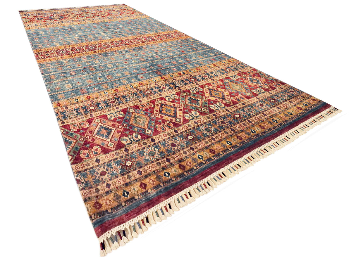 Khorjin-style rug angled view with multicolor geometric bands and cream fringe trim.