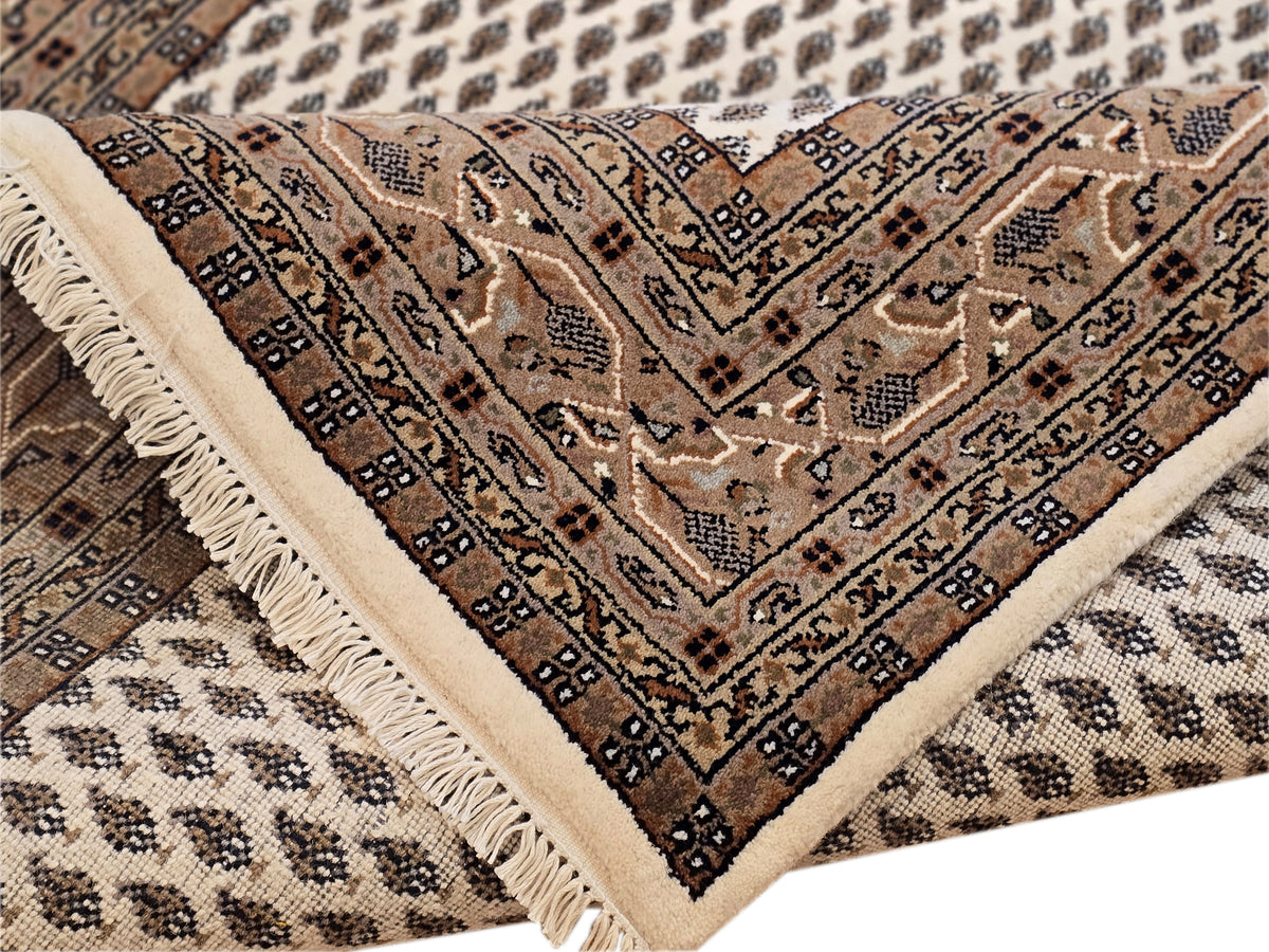 Rug corner detail with dark geometric border, cream field, and short fringe