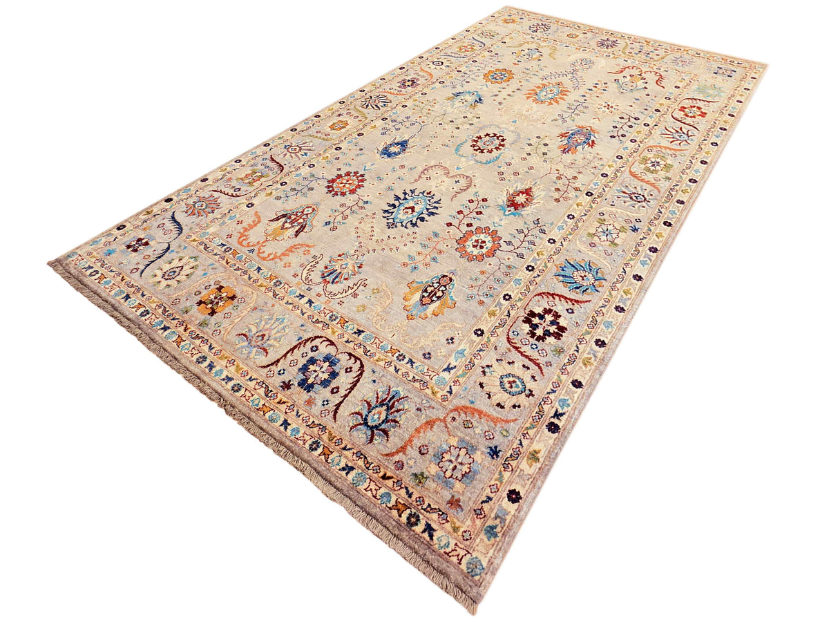 Beige area rug with scattered floral forms, navy blue accents, and fringed border