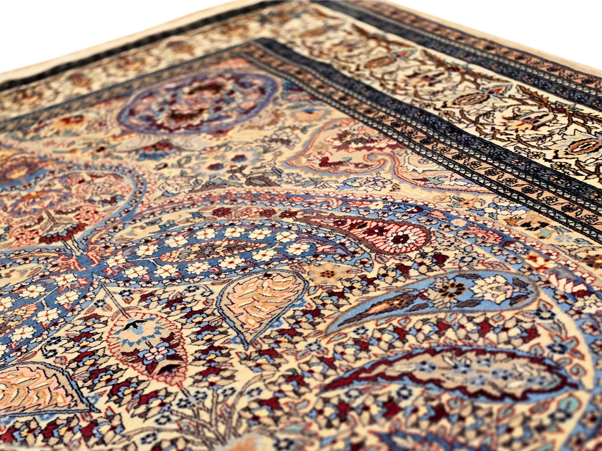 Close-up view of blue Tabriz-style rug with swirling motifs and ornate medallion pattern.