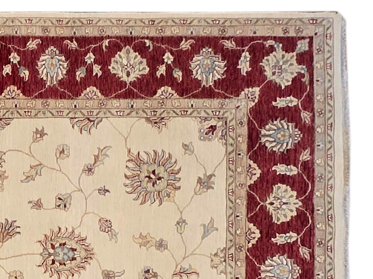 Wool rug close-up: cream field with burgundy side border and floral motifs