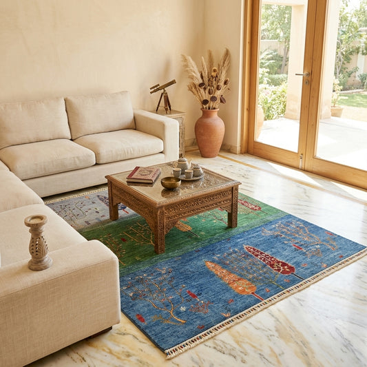 Area rug with blue field, green band, orange tree motifs, and beige fringed edge.