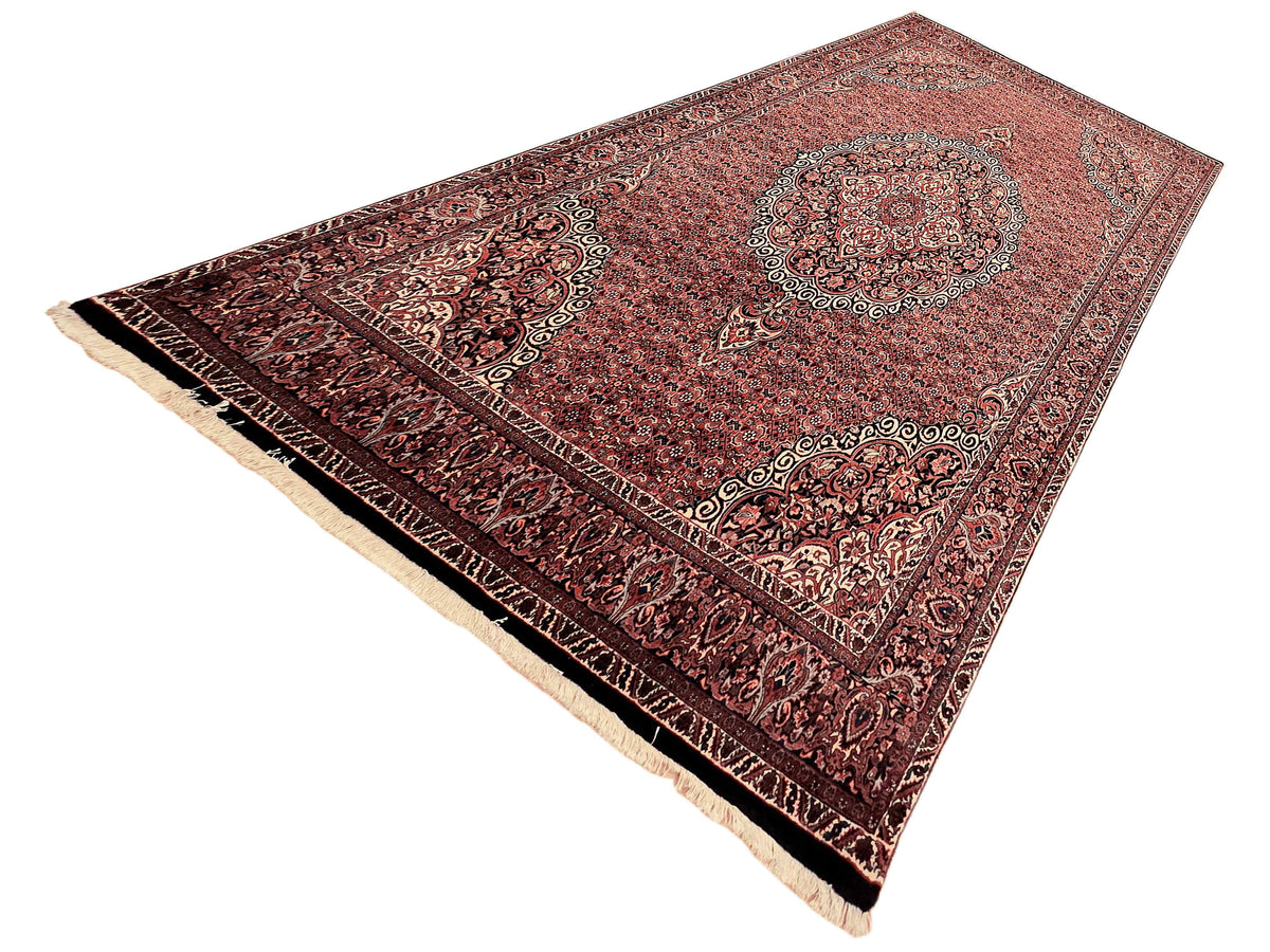 Terracotta and dark red area rug with medallion design and cream fringed edge