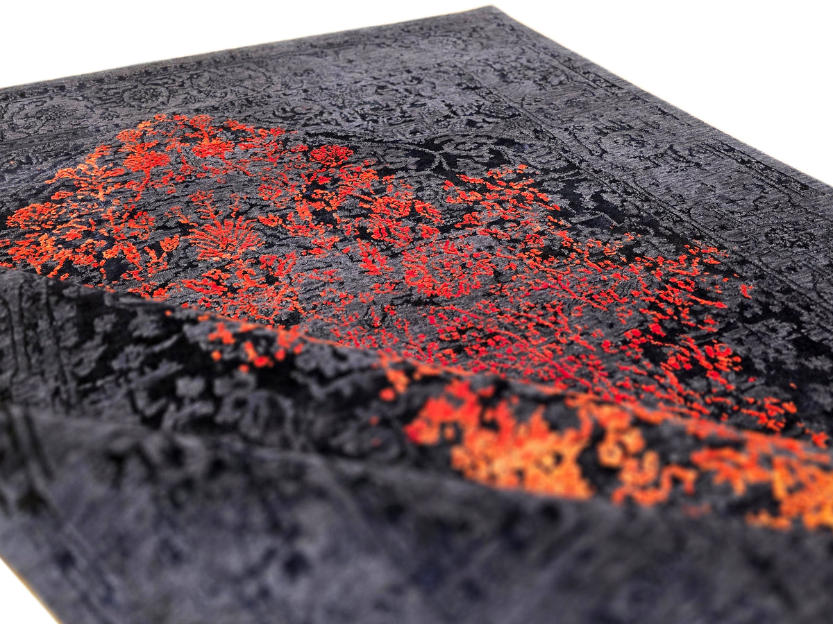 Navy textured area rug with bold orange-red abstract motif on surface