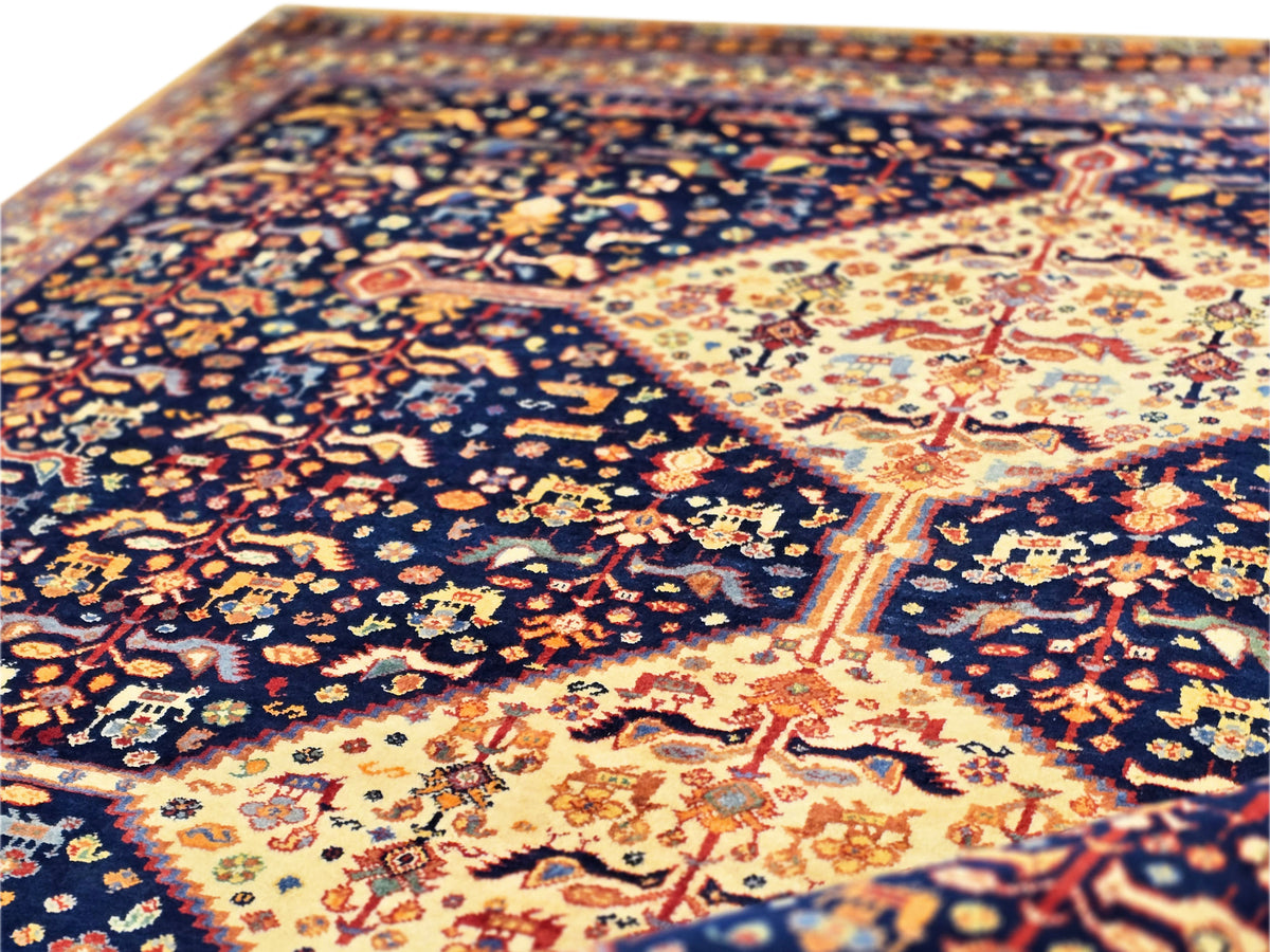 Close-up of navy rug with cream central motif and dense orange floral accents