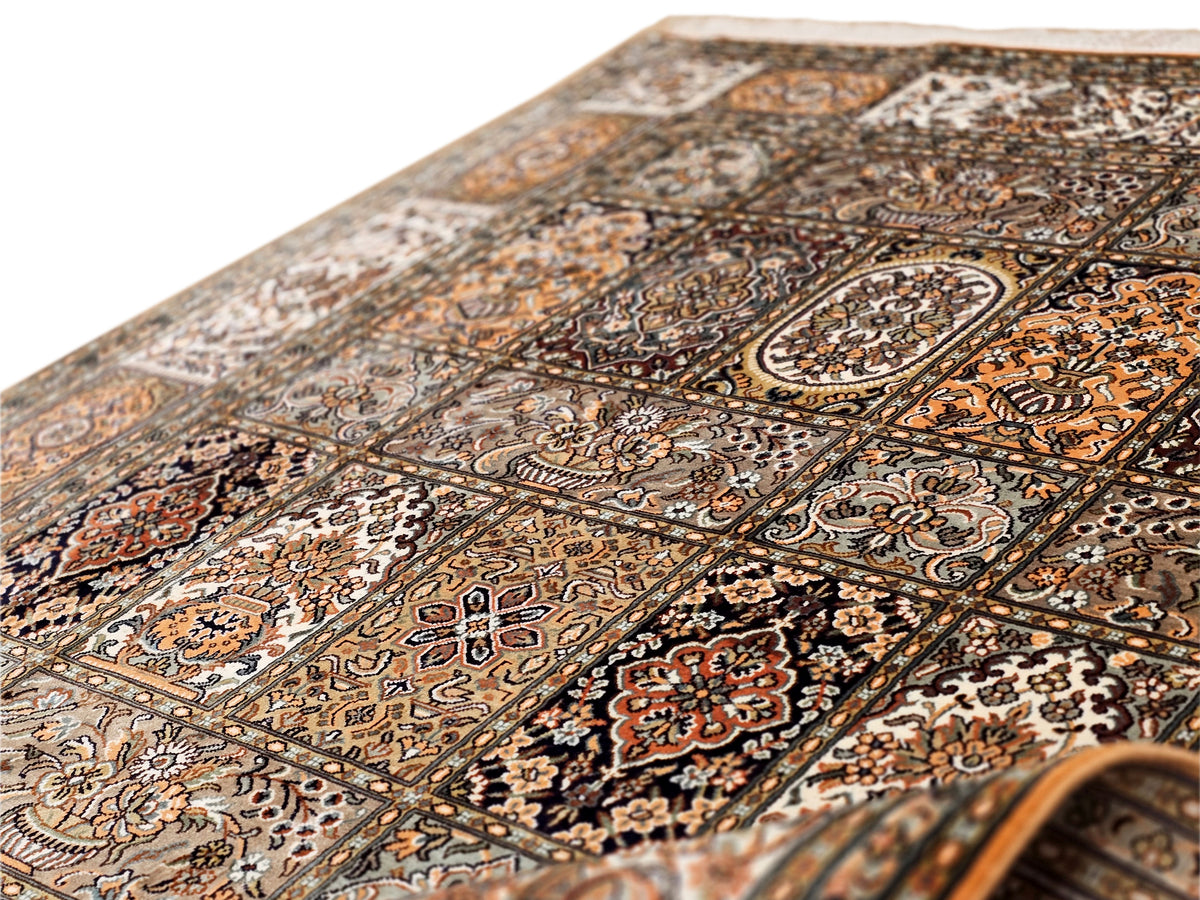 Silk rug close-up of intricate border motifs and floral medallions in brown and gold.