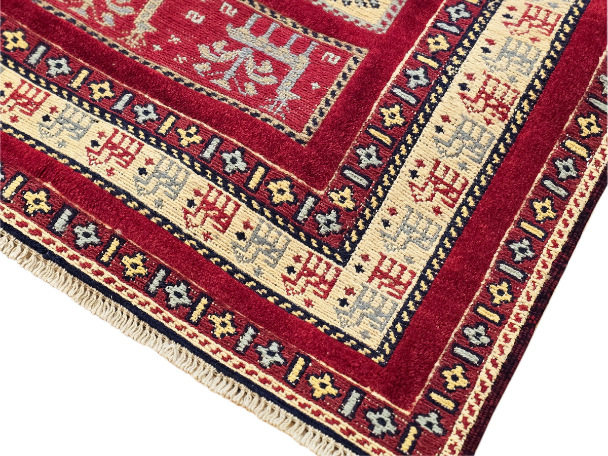 Close-up of rug edge with red background, cream fields, and navy details