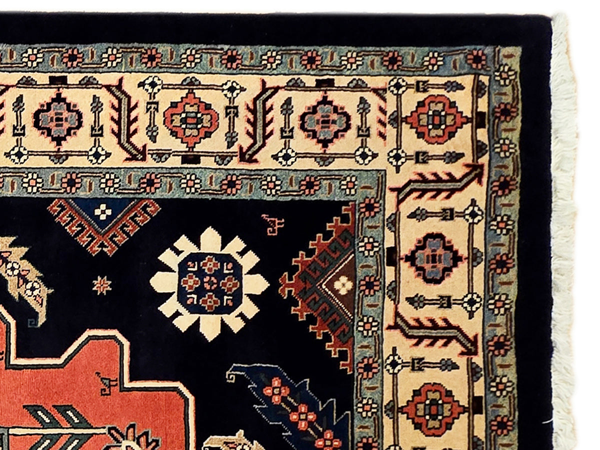 Close-up of navy rug pattern with cream and red medallions and cream fringe edge