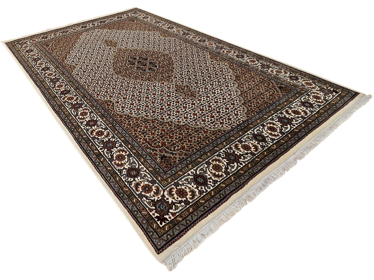 Darker brown patterned area rug with central medallion, ivory ornament border, fringes.