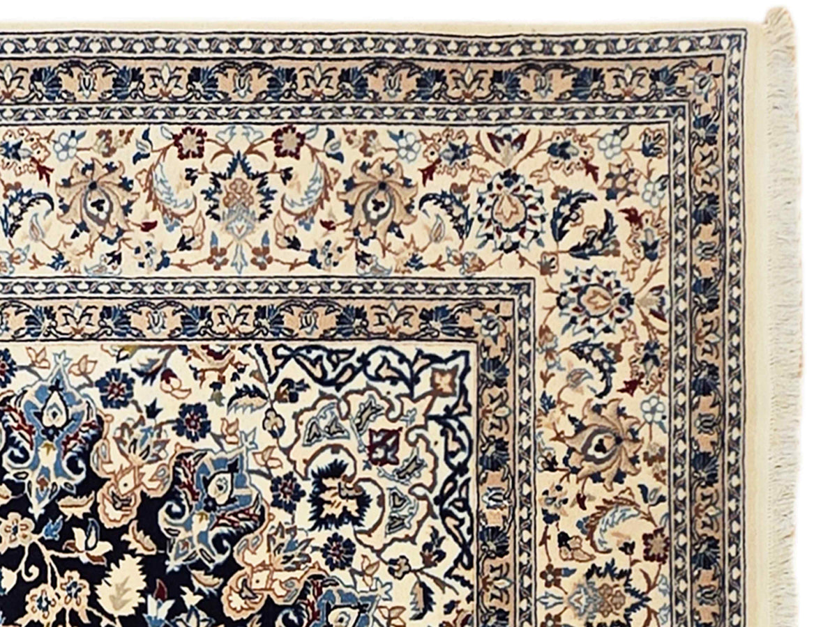 Nain rug close-up of cream field with navy floral vines and decorative border trim.