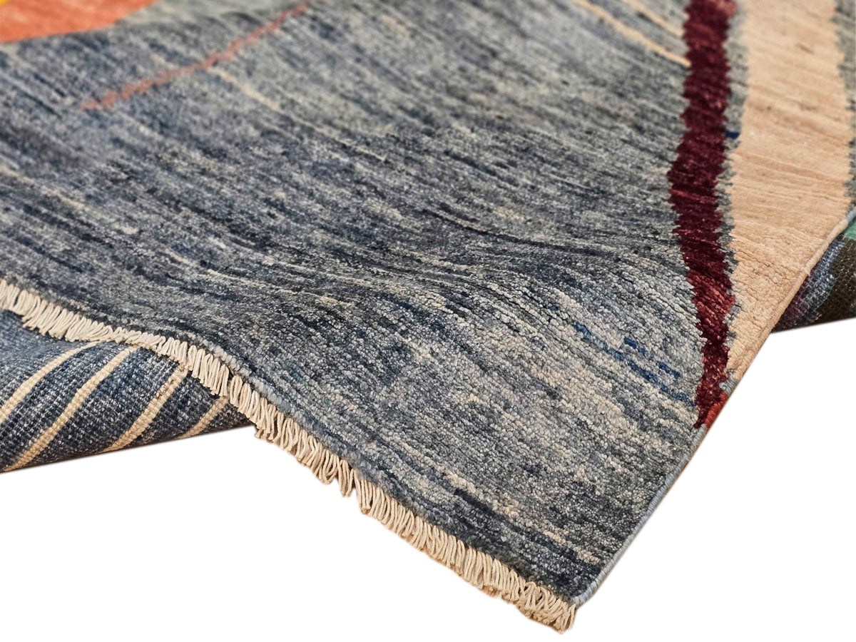 Edge of abstract area rug with gray pile and multicolor striped design plus fringe