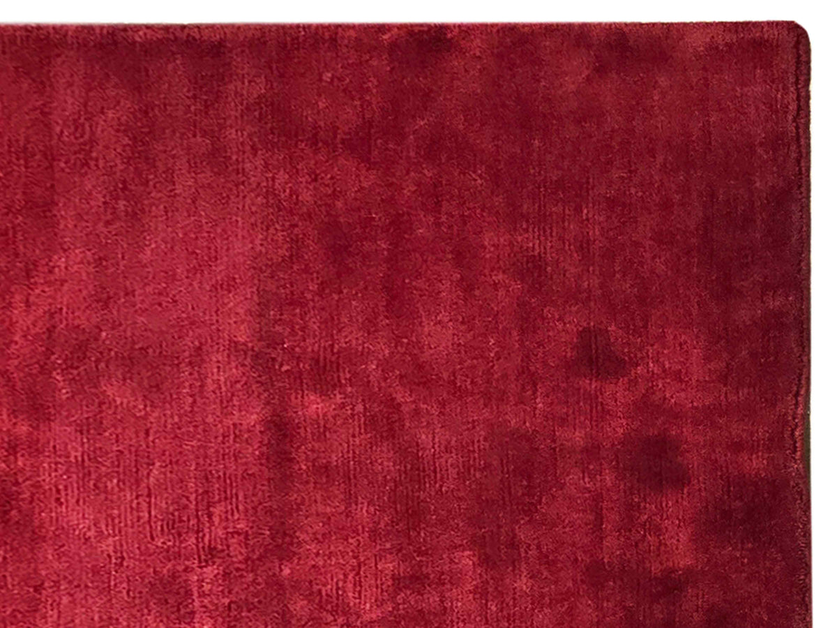 Red rug close-up showing fine woven texture and neatly finished border