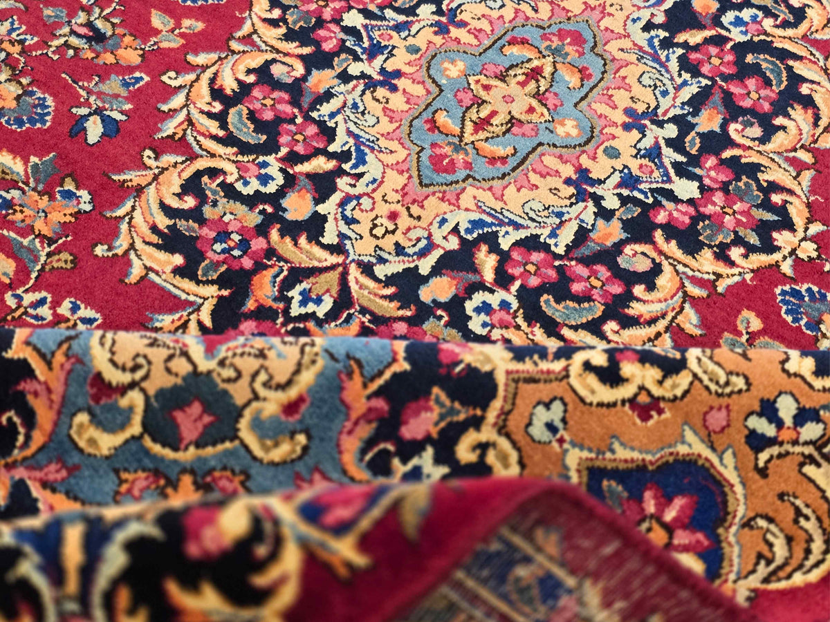 Close-up of red rug fabric with colorful floral vines and navy accents