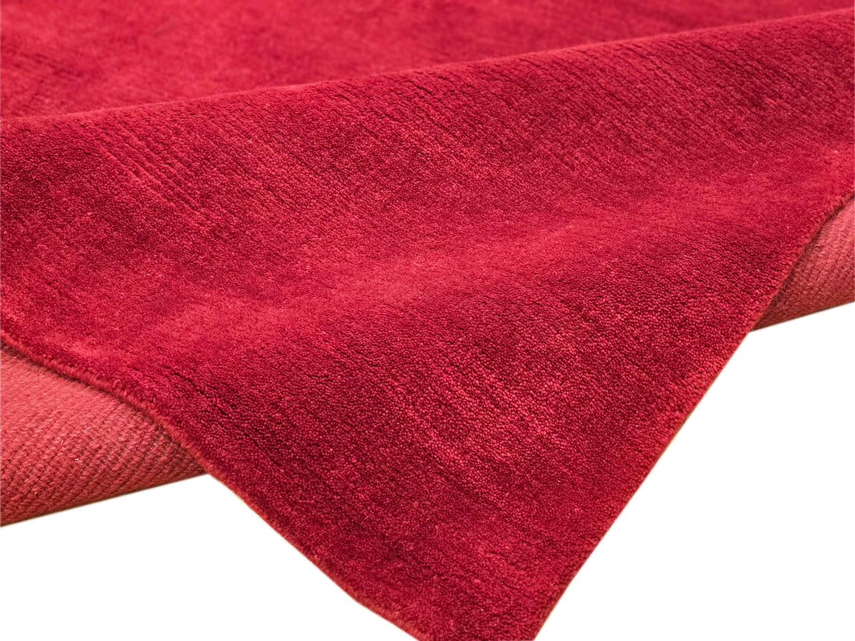 Red rug corner detail with low-pile texture and folded-over edge section