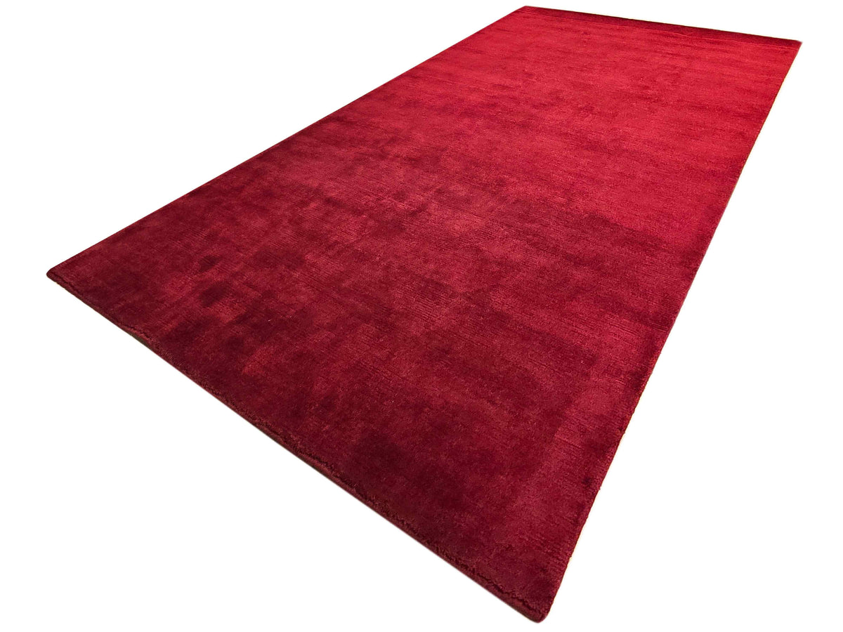 Red rug, rectangular shape, textured surface with dark maroon tone at edges