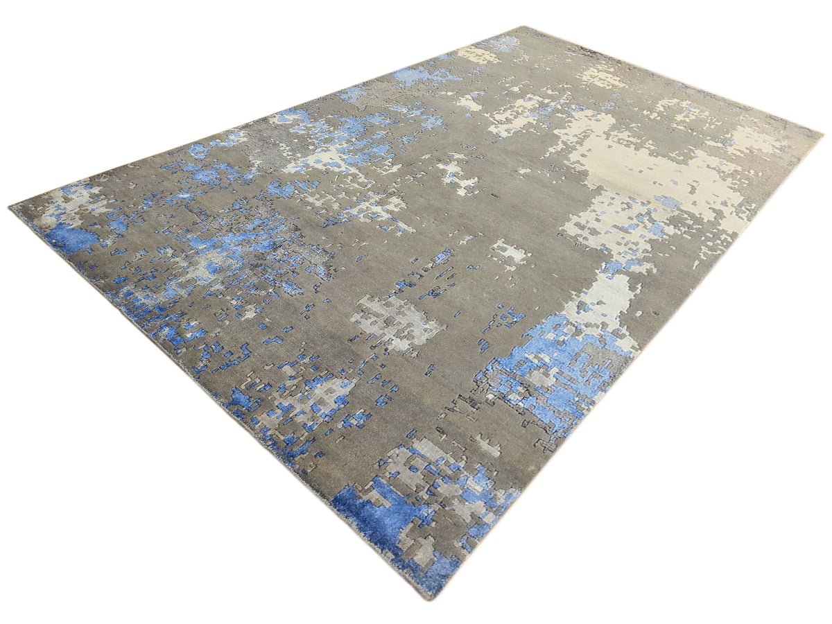 Modern abstract area rug in gray and blue with cream highlights, angled view