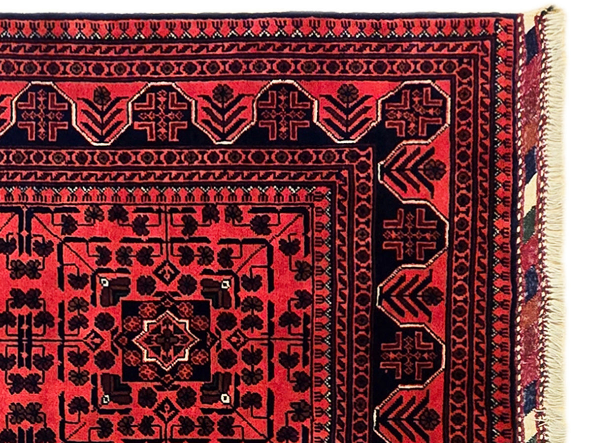 Red rug with navy geometric motifs and beige fringe edge
