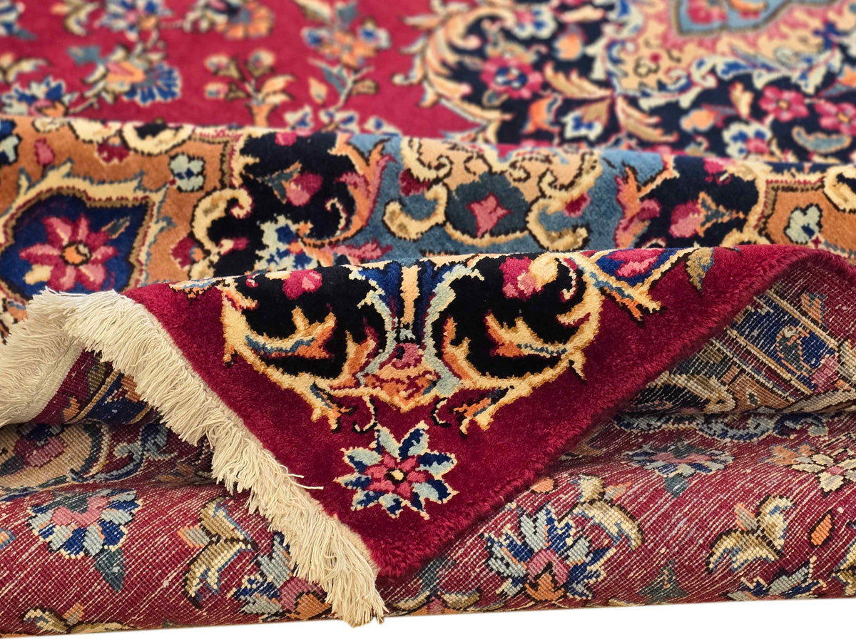 Close-up corner of red rug showing fringe and beige backing