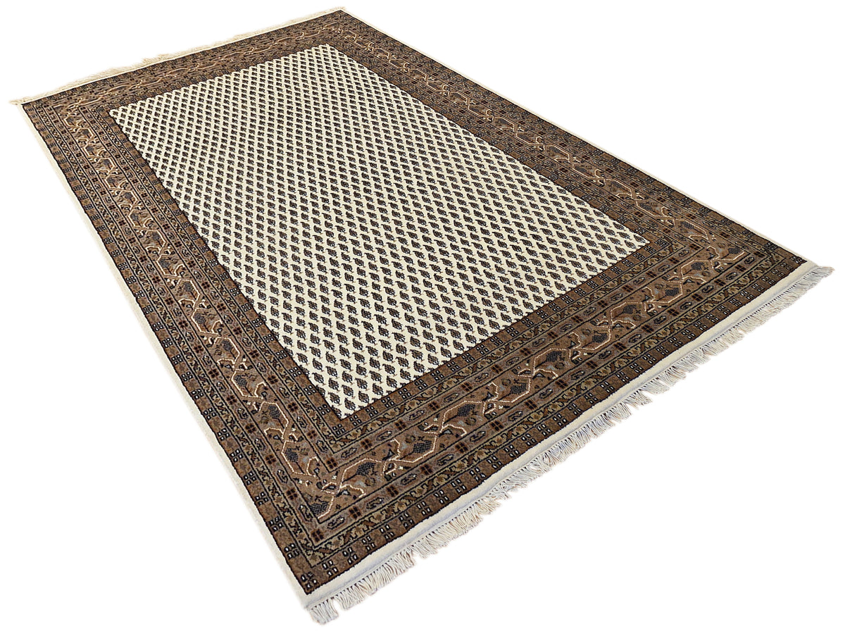 Fringed area rug with dark ornate border and white crosshatched lattice center