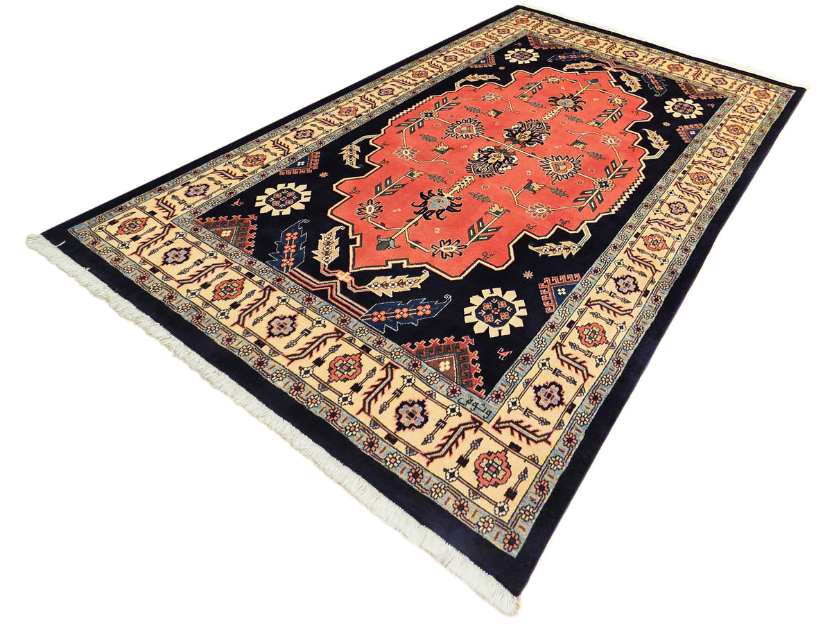 Rectangular rug with orange center panel on dark navy background and cream ornamental border