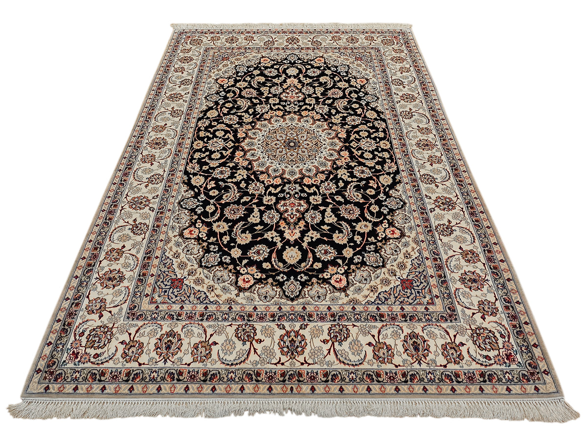 Isfahan rug with central black floral medallion, cream lattice border, and pale fringe
