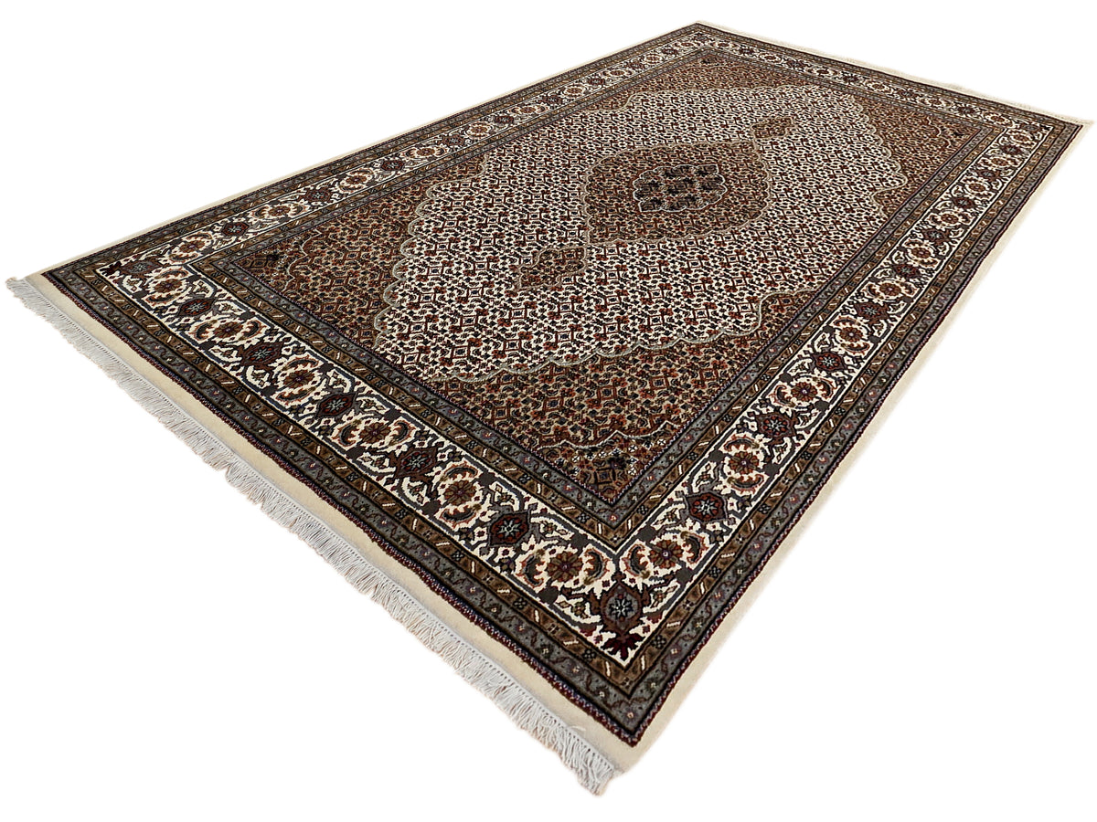 Smaller triangular perspective of patterned area rug with central medallion and fringes.