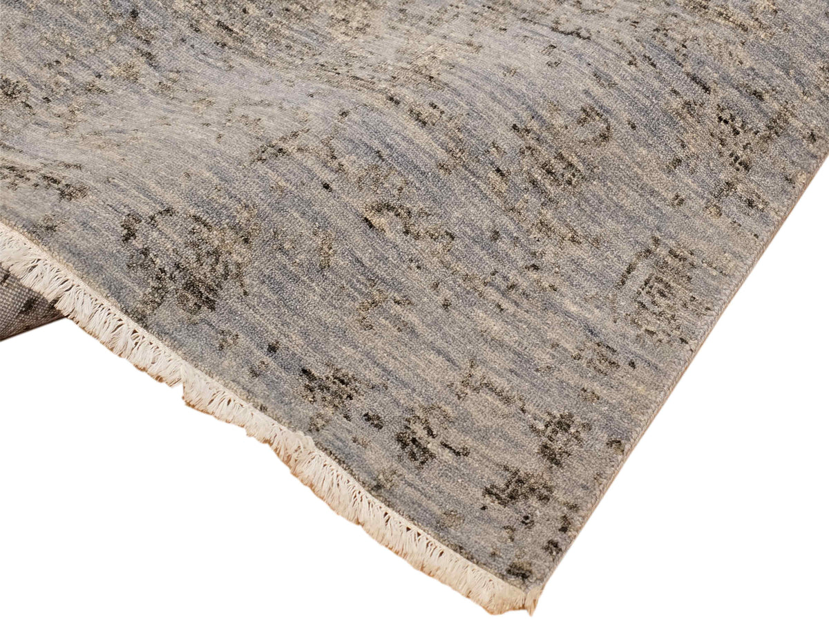 Light gray distressed rug corner with short fringed border