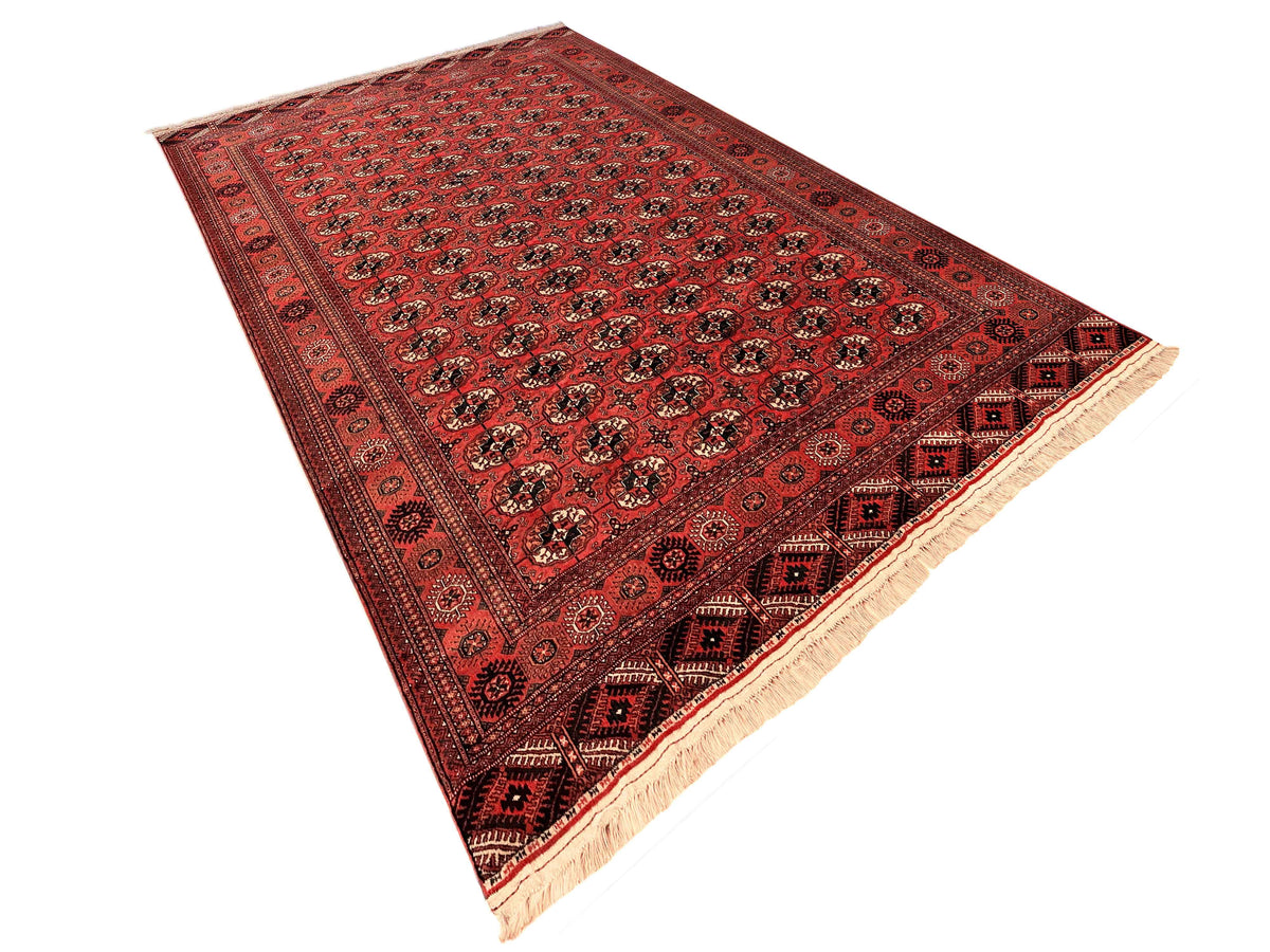 Red rug with symmetrical medallion field, dark border bands, and cream fringe