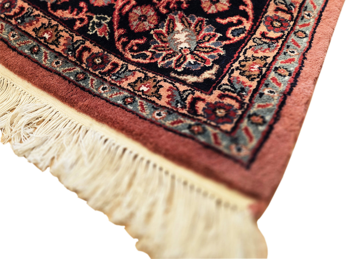 Terracotta rug corner close-up with floral pattern and cream fringe tassels