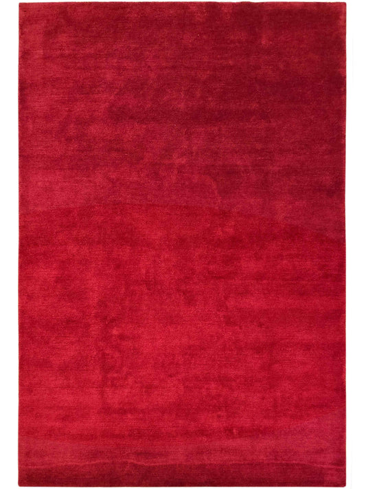 Solid red rectangular rug with mottled finish and tightly bound perimeter