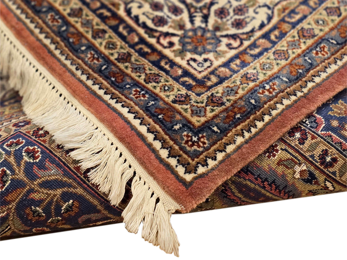 Corner detail of multicolor Qum-style rug with cream fringe and patterned trim