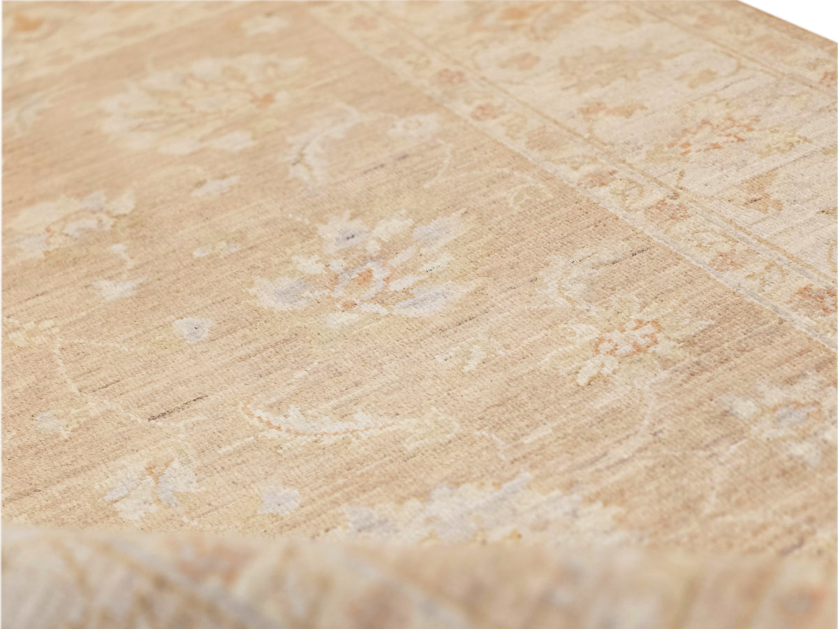 Beige rug close-up with worn speckled texture and faded abstract floral motifs