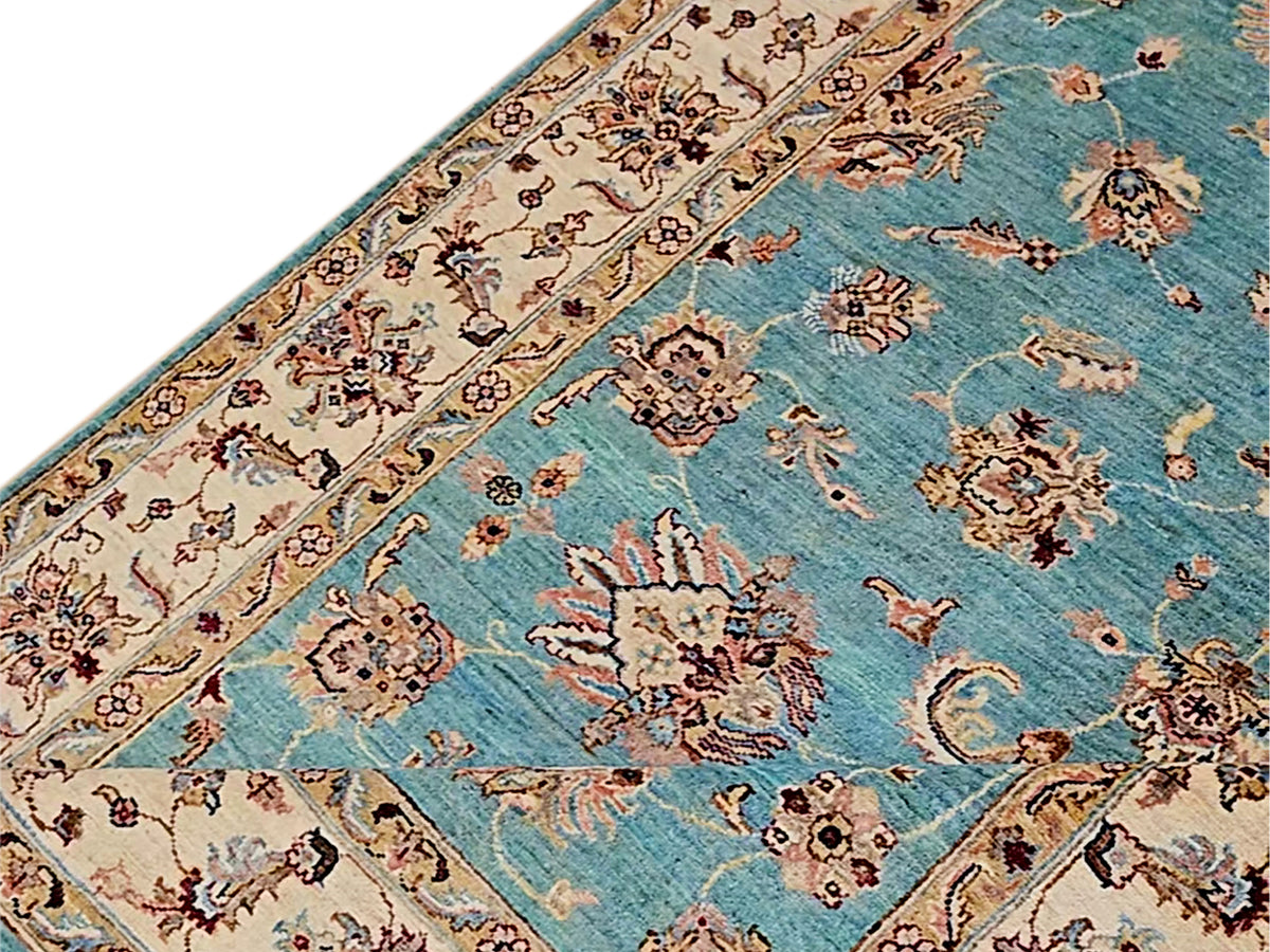 Close-up corner of turquoise rug with ivory border bands and floral motifs