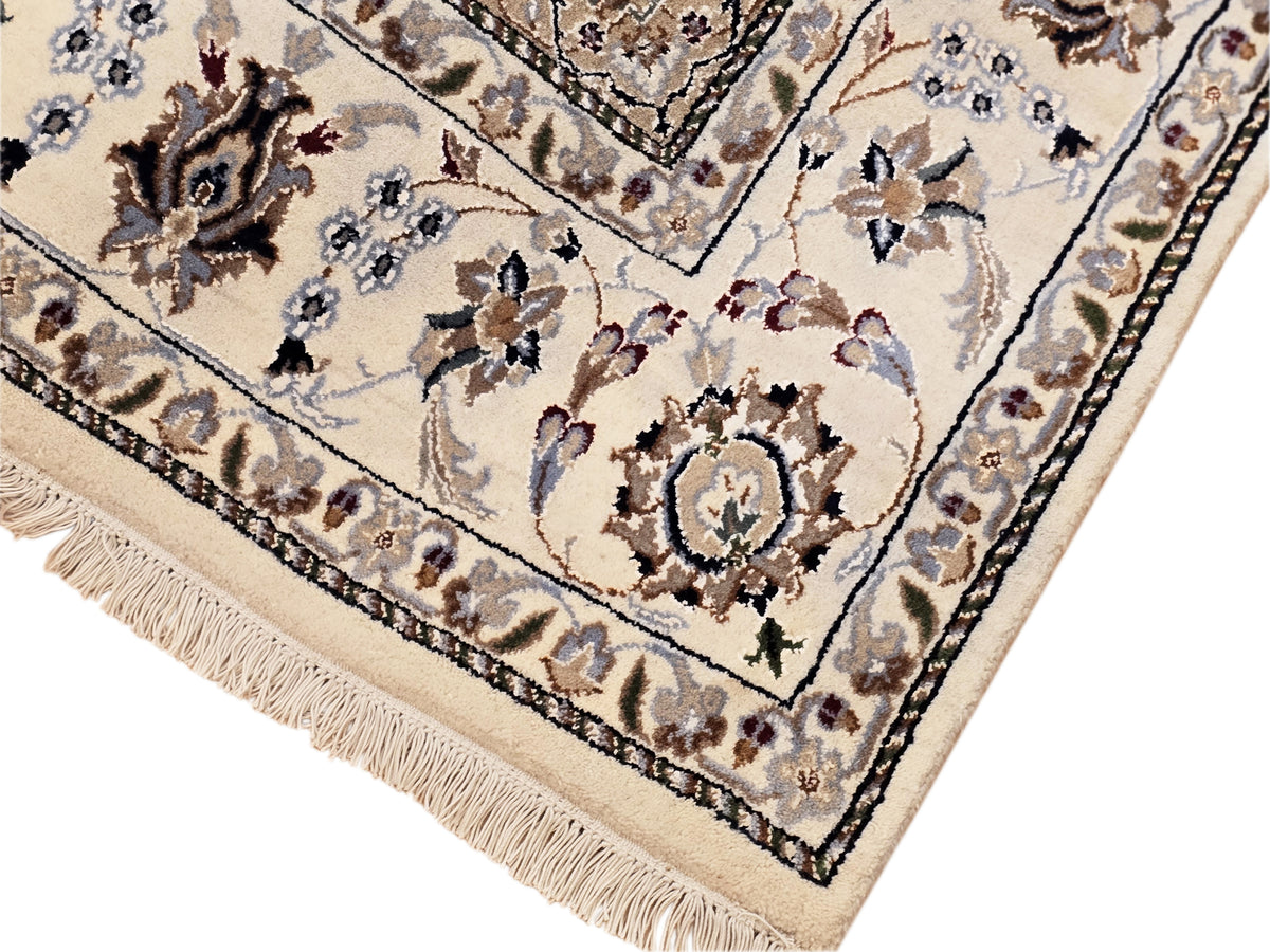 Nain rug corner detail with ivory ground, navy floral motifs and braided fringe trim