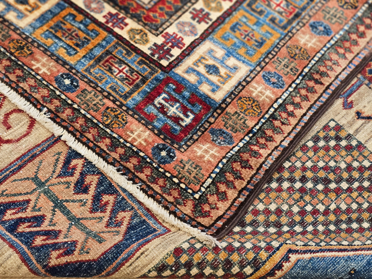Kazak-style rug corner with fringed edge and diamond geometric motifs in blue and rust